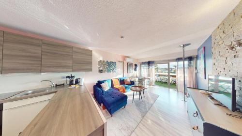 - une cuisine et un salon avec un canapé bleu et une table dans l'établissement Le Melrose Port Nature 5 Village Naturiste Cap d'Agde, au Cap d'Agde