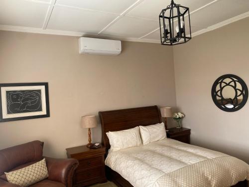 1 dormitorio con 1 cama, 1 silla y ventilador en On De La Vigne, en Riviersonderend