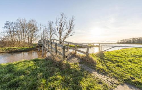 a wooden bridge over a river next to a field at Stunning Home In Wagenborgen With Wifi in Wagenborgen