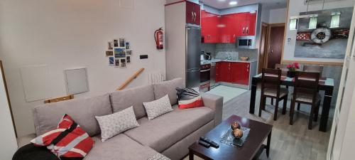 a living room with a couch and a kitchen with red cabinets at Apartamentos Turísticos "El Jardín" in Teruel