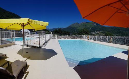 ein großer Pool mit Sonnenschirm und Stühlen in der Unterkunft Chalets du Lac in Arcizans-Avant