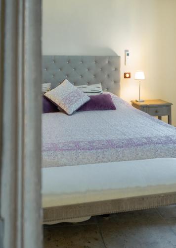 a bedroom with a large bed with purple pillows at La Belle Vie in Saint-Hilaire-dʼOzilhan