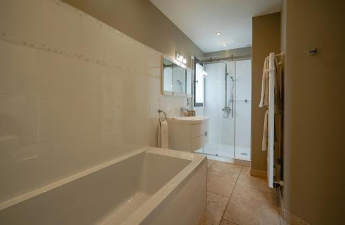 a white bathroom with a tub and a sink at La Belle Vie in Saint-Hilaire-dʼOzilhan