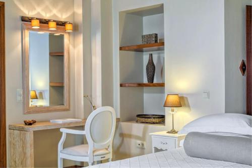 a bedroom with a bed and a mirror and a chair at Mare Monte Luxury Suites in Spetses
