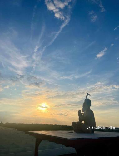 a person sitting on a table looking at the sunset at Bubble World Wild Love in Adelfia