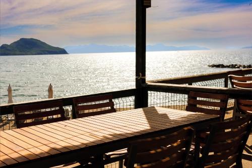 a wooden table and chairs next to the water at Bodrum Ada Apart Otel Turgutreis in Mugla