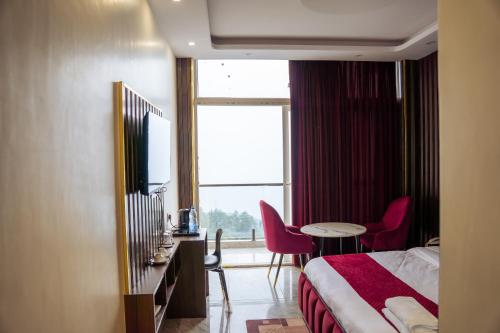 a hotel room with a bed and a table and chairs at Aroma & U in Kūfrī