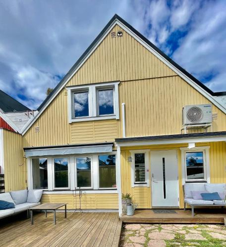 a yellow house with a deck at Charming Family Home in the Heart of the Archipelago only 30 Minutes from Central Stockholm in Gustavsberg