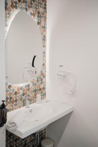 a white bathroom with a sink and a mirror at Hotel Ficocella in Palinuro