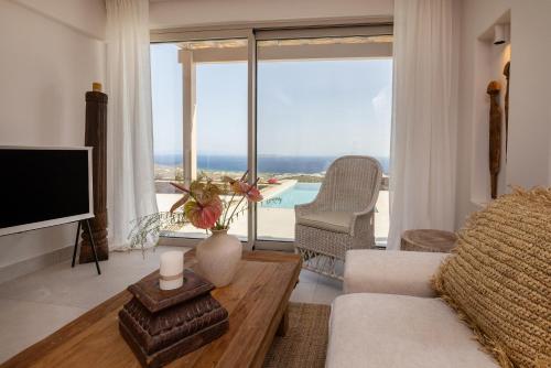 a living room with a television and a large window at Soborgo Exquisite Villas in Tinos Town