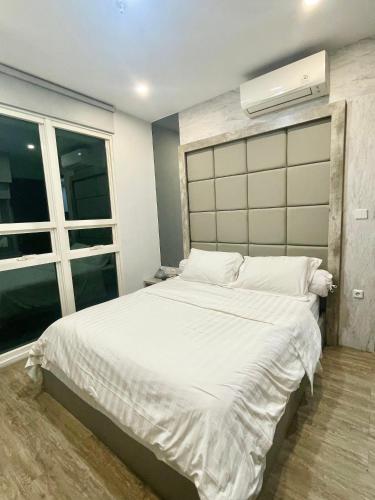 a bedroom with a large white bed and a window at 2BR Peaceful & Cozy Family Condo in Jakarta