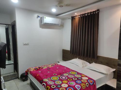 a bedroom with a bed with a colorful blanket on it at Hotel RB Palace in Indore