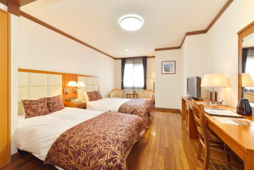 Habitación de hotel con 2 camas y escritorio en Asahidake Onsen Hotel Deer Valley, en Higashikawa