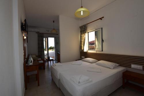 a bedroom with a large white bed and a desk at Morpheas Rooms in Palaiochóra