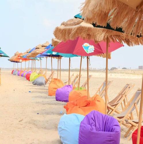 a row of beach chairs and umbrellas on a beach at شاليه مميز بقريه مارينا دلتا السياحيه olooool8369 in Al Ḩammād