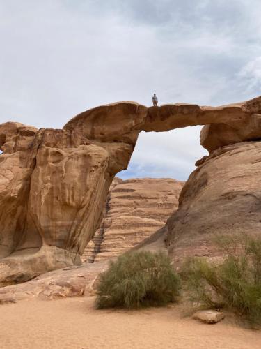 un homme debout sur un pont de pierre dans le désert dans l'établissement Wadi Rum Cave Experience, à Wadi Rum