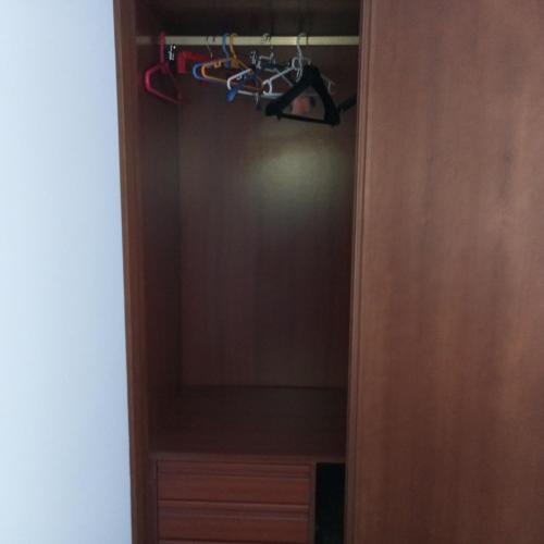 a closet with a wooden door with hangers at Casamapi in O Pindo