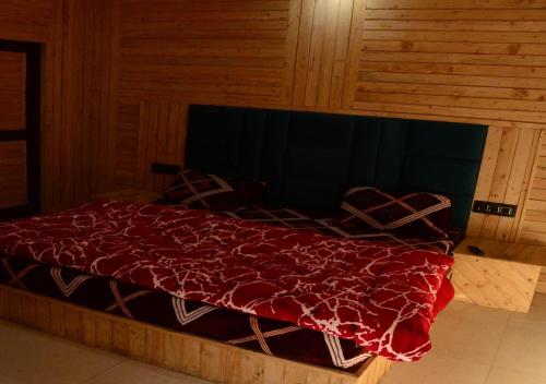 a bed with a red blanket on top of it at Green valley homestay in Khajjiar 