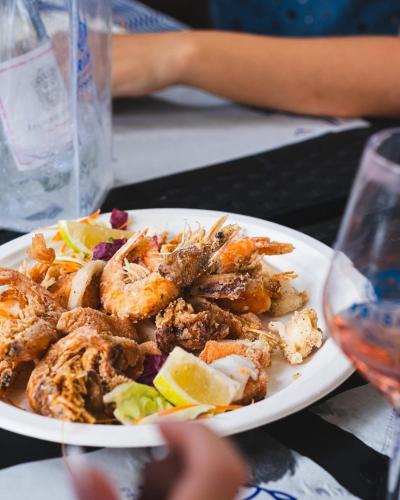a plate of shrimp on a table with a glass of wine at Porta Piccola Residence in Castellaneta