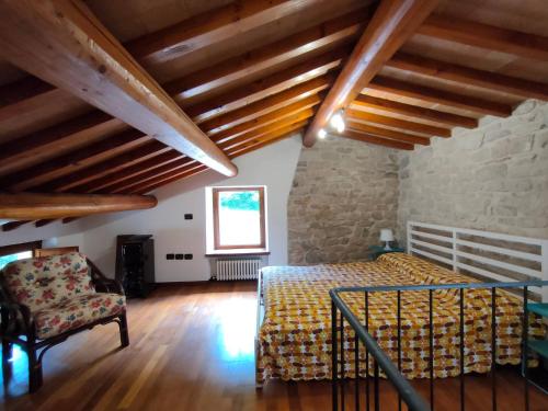 a bedroom with a bed and a chair and wooden ceilings at Cottege in Pietra sul Fiume in Frontone