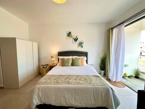 a bedroom with a large bed and a large window at The Olive Beachfront Apartment & Spa in Bahçeli
