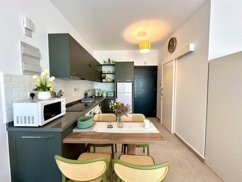 a kitchen with a table with chairs and a microwave at The Olive Beachfront Apartment & Spa in Bahçeli