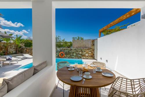a patio with a wooden table and chairs and a pool at Clementina Paros in Naousa