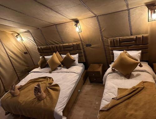 a bedroom with two beds in a tent at Desert Nights Camp in Merzouga