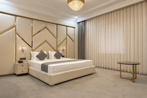 a bedroom with a large white bed and a table at Porto Bello Hotel in Tashkent