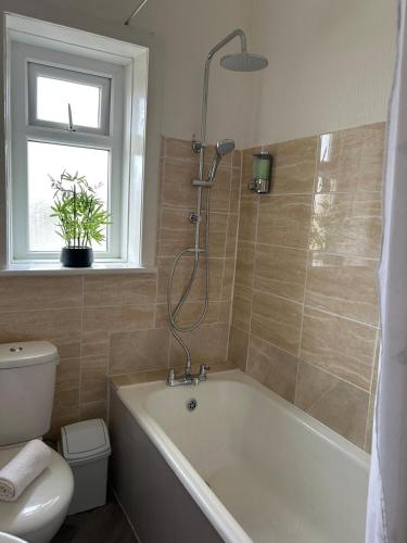 a bathroom with a tub and a toilet and a window at Chapel house-M65- Hospital- parking-shops-food in Nelson