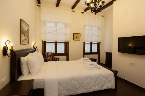 a bedroom with a bed with white sheets and a tv at White House Boutique Hotel & Restaurant - since 1999 in Berat