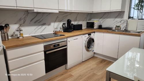 a kitchen with white cabinets and a washer and dryer at Cervantes Prime in Valencia