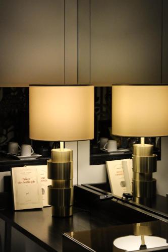 two lamps sitting on a table with books at Hotel Montalembert in Paris