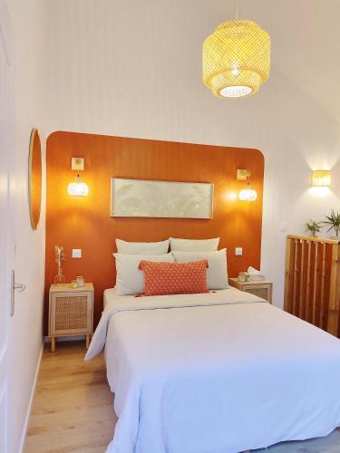 - une chambre avec un grand lit blanc et une tête de lit orange dans l'établissement Écrin Terracotta, à Clermont-Ferrand