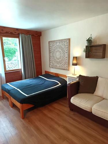 a bedroom with a large bed and a couch at Les Chalets d'Arlos in Arlos