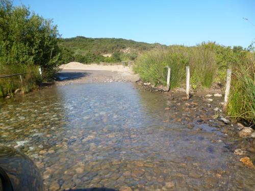 a stream of water next to a dirt road at Casa vacanze con terrazza panoramica vista mare in Portu Maga