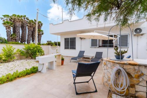 a patio with a table and chairs and an umbrella at Alba Salentina by BarbarHouse in Torre rinalda