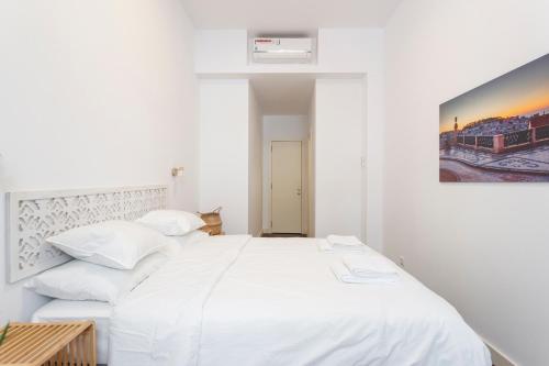 a white bedroom with two beds and a painting on the wall at StayBA Guesthouse in Lisbon