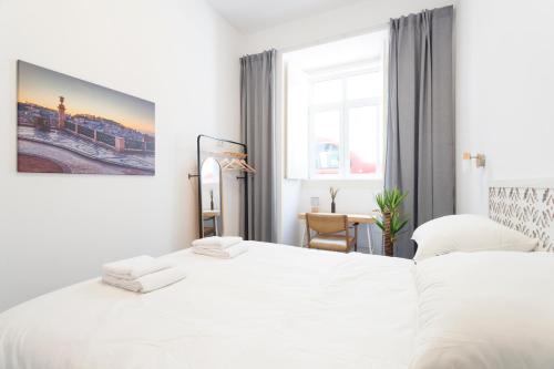 a white bedroom with a bed and a window at StayBA Guesthouse in Lisbon