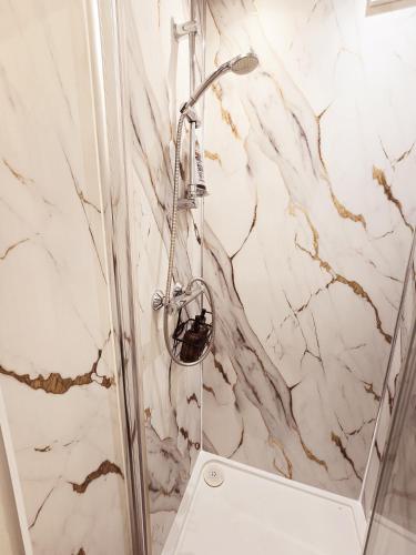 a shower in a bathroom with a marble wall at Alross Guest House with Italian Breakfast in London