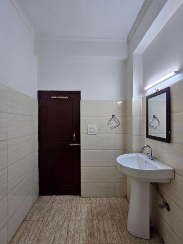 a bathroom with a sink and a black door at Hotel City Gold - Hotel in Dharamshala in Dharmsala