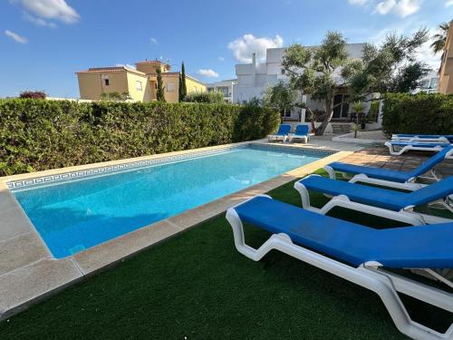 a swimming pool with two blue lounge chairs next to it at VILLA BLANCA in Cala Ferrera