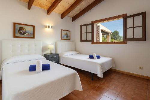 a bedroom with two beds and a window at Villa Ca Na Magdalena By homevillas360 in Pollença