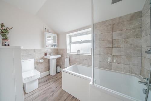 a bathroom with a tub and a toilet and a sink at The Beach House in Melcombe Regis