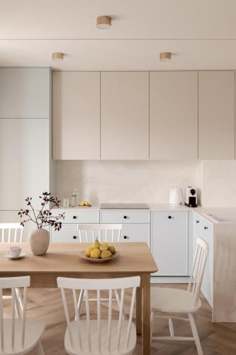 a kitchen with a wooden table and white cabinets at Piwna Apartamenty nad morzem Władysławowo in Władysławowo