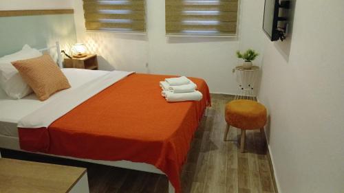 a bedroom with a bed with orange blanket and a chair at Kavala Hotel Bodrum in Bodrum City