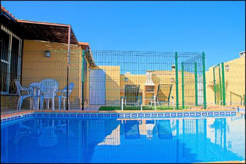 einen Zaun neben einem Pool mit Stühlen in der Unterkunft Bungalow Curro Pareja 131 in Conil de la Frontera