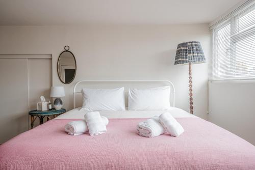 a bedroom with a pink bed with towels on it at The Beach House in Melcombe Regis