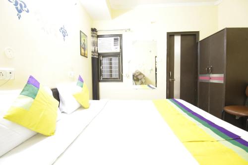 a bedroom with a large white bed with colorful pillows at Hotel Satyam Swagat in Jawālāpur
