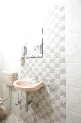a white bathroom with a sink and a mirror at Hotel Satyam Swagat in Jawālāpur